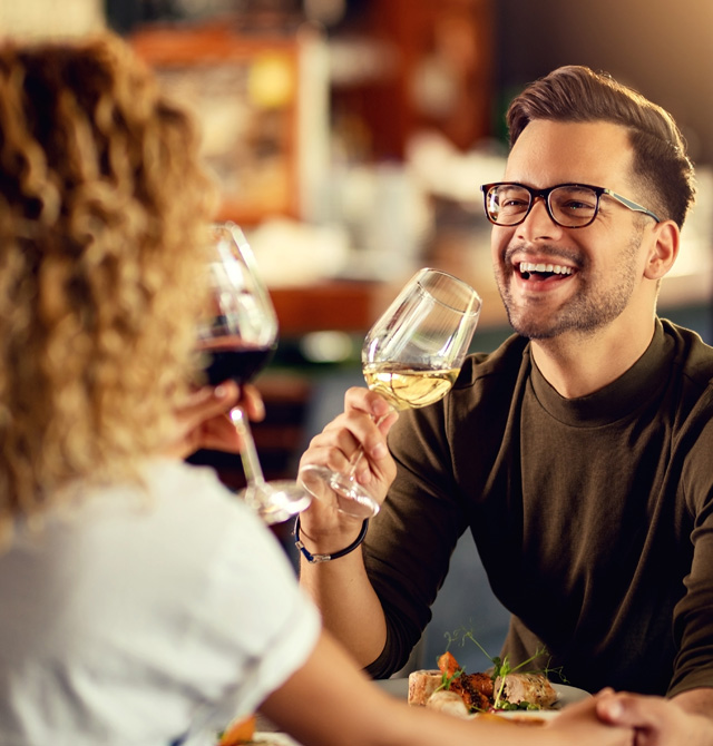 Ein lachender Mann genießt ein Glas Wein mit einer Frau